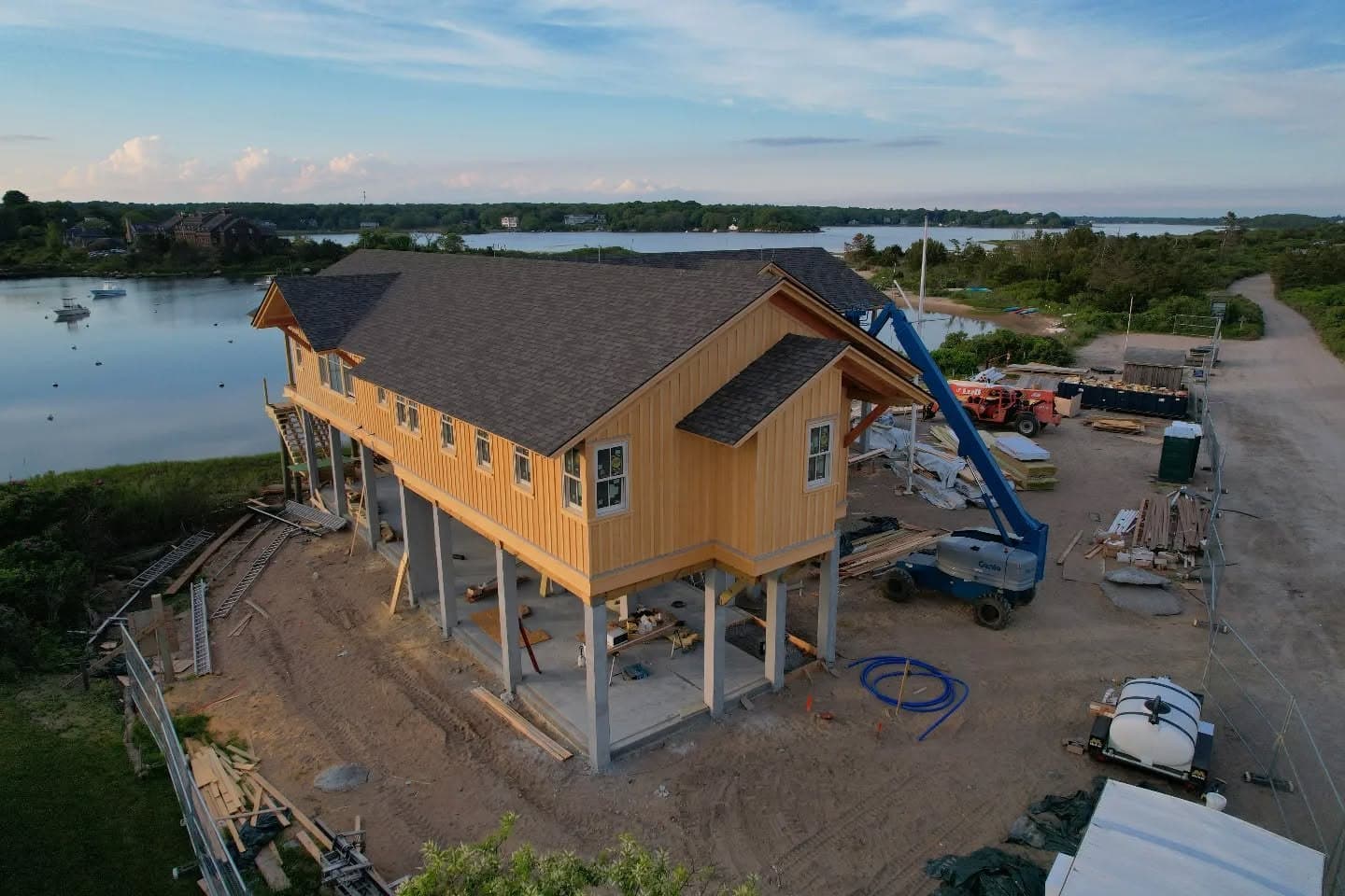 Aerial view of a raised home under construction near the water in Weekapaug, Rhode Island