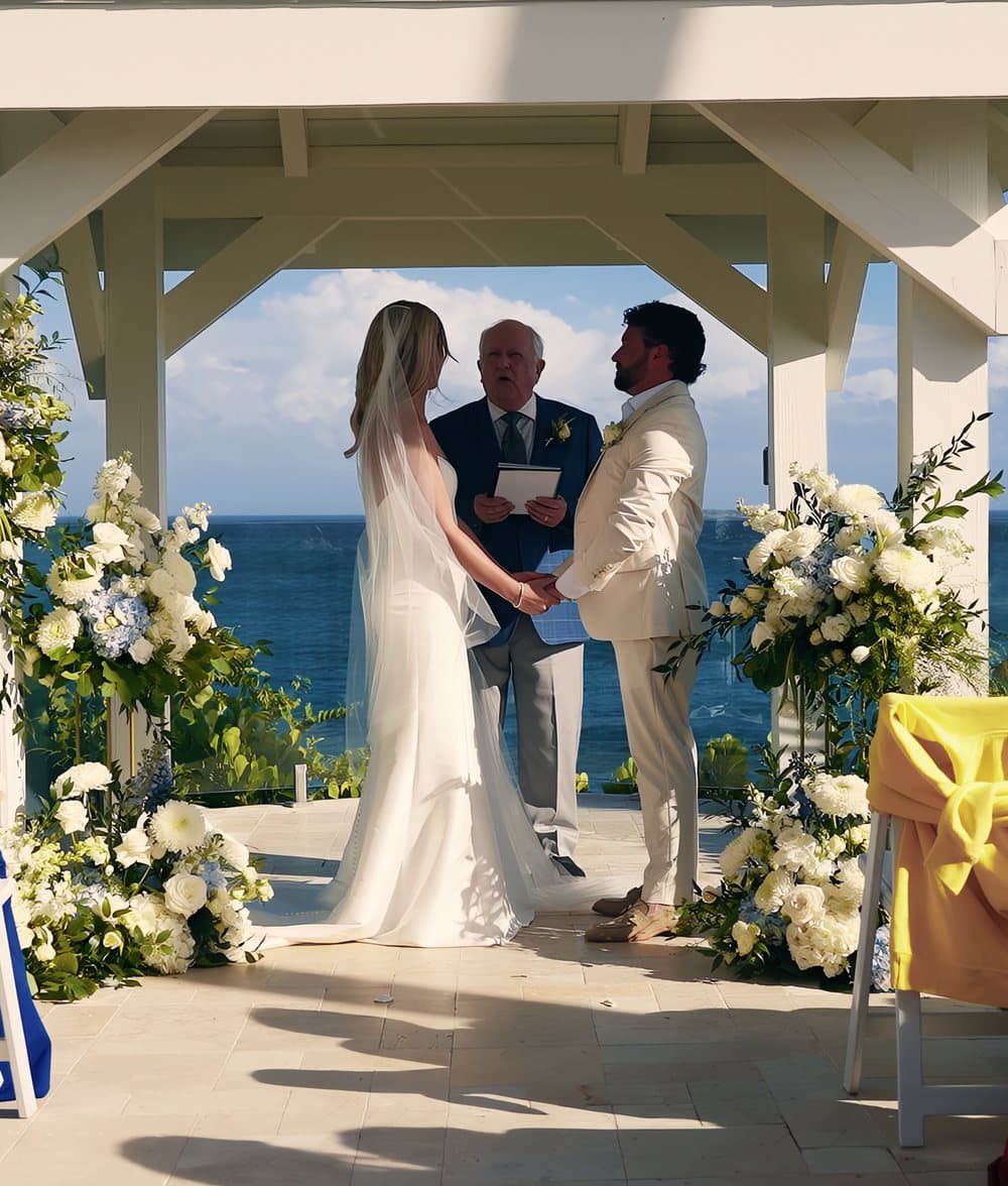 A bride and groom exchanging vows under a white gazebo above the sea in the Virgin Islands