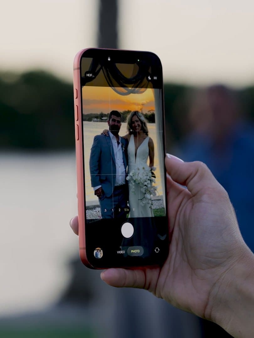 A phone held up to film Andrea and Kevin by the water, the couple framed on its screen